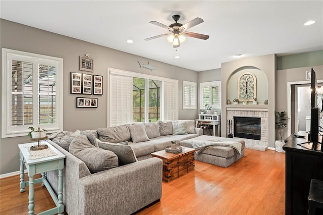 living room featuring baseboards, a fireplace, wood finished floors, and a ceiling fan