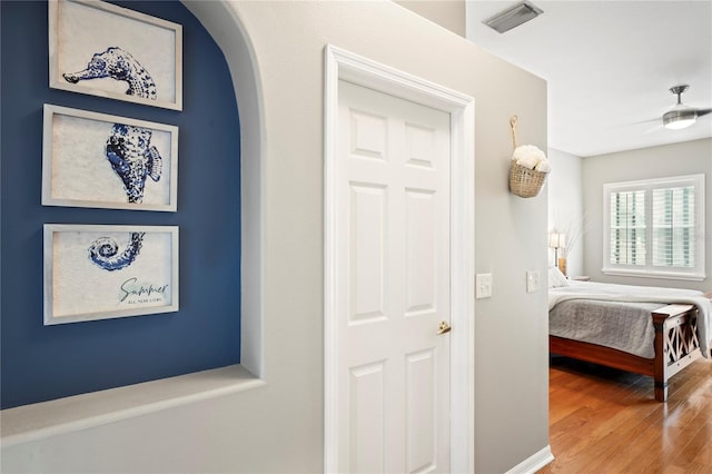 corridor featuring arched walkways, visible vents, and wood finished floors