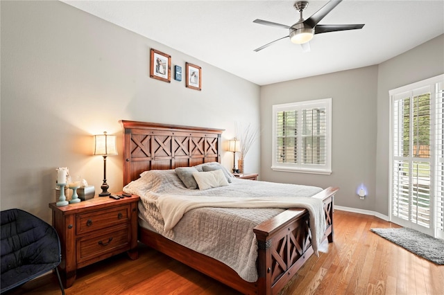 bedroom with light wood-style flooring, a ceiling fan, and baseboards