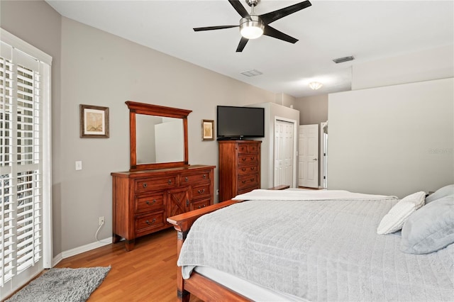 bedroom with ceiling fan, light wood-style floors, visible vents, and baseboards