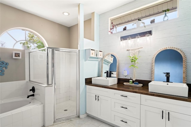 bathroom featuring a sink, a garden tub, a stall shower, and double vanity