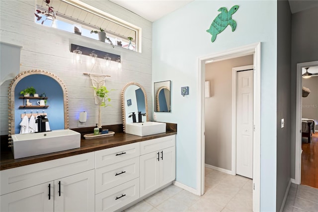 full bathroom featuring tile patterned flooring, double vanity, baseboards, and a sink