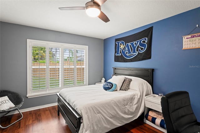 bedroom with ceiling fan, baseboards, and dark wood-style floors