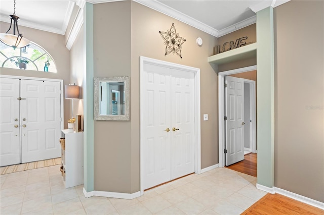 foyer entrance with light tile patterned flooring, crown molding, and baseboards