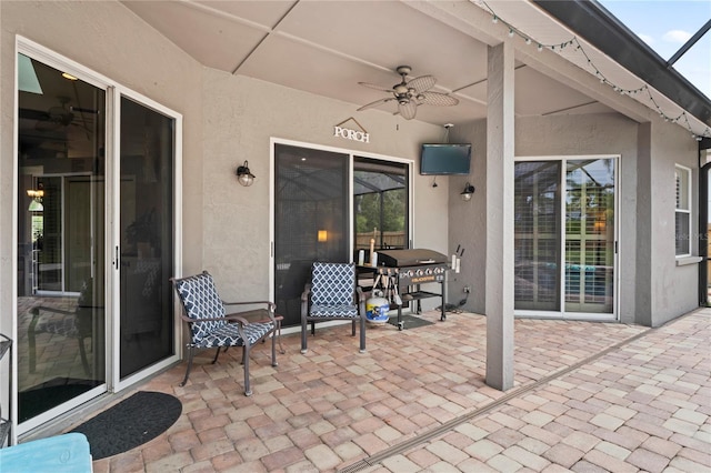 view of patio / terrace with glass enclosure, area for grilling, and a ceiling fan