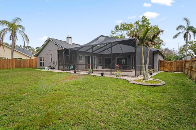 back of property with a lanai, a lawn, a chimney, a fenced backyard, and a patio area