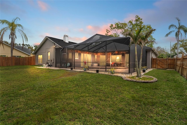 back of house with a yard, a fenced backyard, a chimney, a lanai, and a patio area