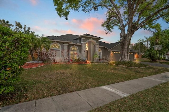 view of front of house featuring stucco siding, concrete driveway, a front yard, and a garage