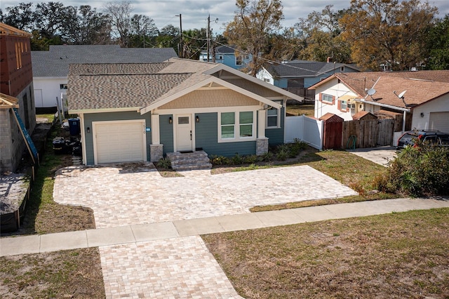 view of front of house with a shingled roof, fence, a residential view, driveway, and an attached garage