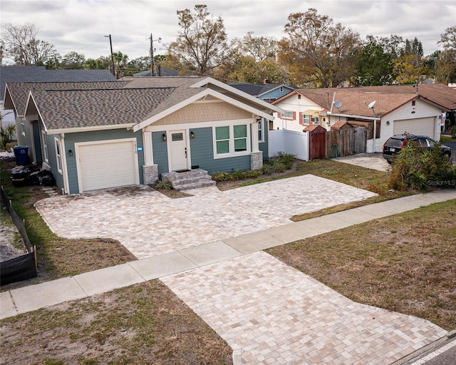 view of front of house with a gate, decorative driveway, fence, roof with shingles, and a garage