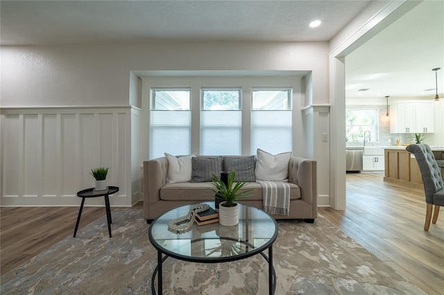 living area featuring a decorative wall, recessed lighting, a wainscoted wall, and light wood finished floors