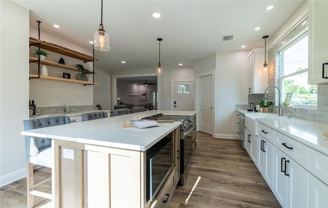 kitchen featuring wood finished floors, visible vents, built in microwave, tasteful backsplash, and a center island