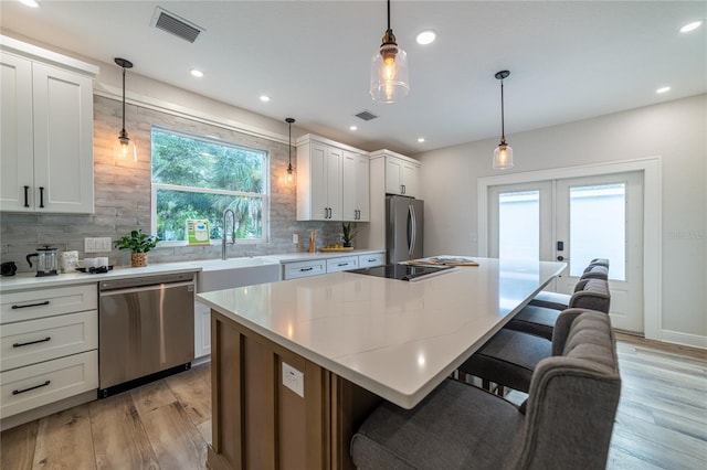 kitchen with visible vents, a kitchen breakfast bar, appliances with stainless steel finishes, and french doors