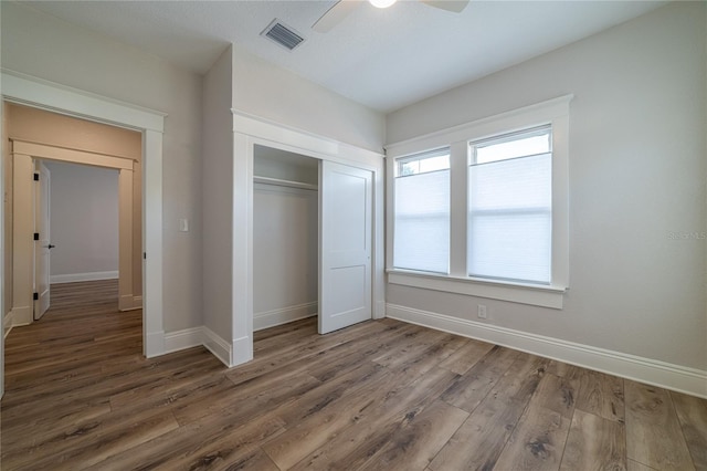 unfurnished bedroom featuring visible vents, a ceiling fan, wood finished floors, a closet, and baseboards