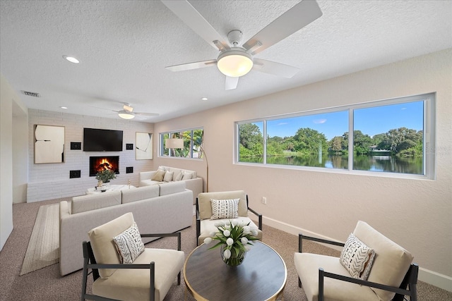 living area featuring a ceiling fan, visible vents, carpet floors, and a textured ceiling