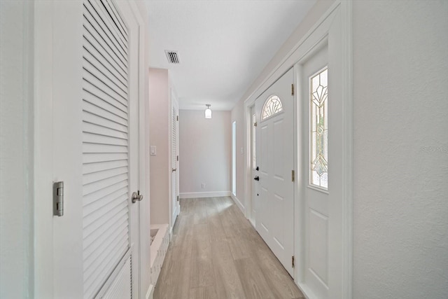 entrance foyer featuring light wood-type flooring, visible vents, baseboards, and a textured wall