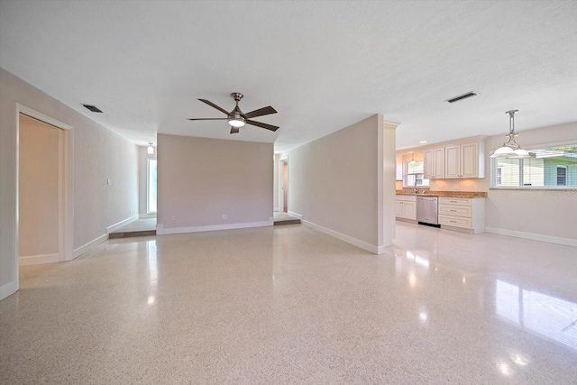 unfurnished living room featuring baseboards, light speckled floor, visible vents, and ceiling fan