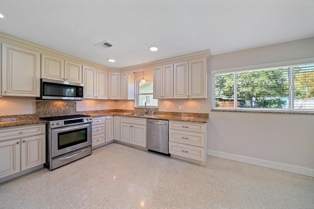 kitchen with baseboards, cream cabinetry, stainless steel appliances, and visible vents