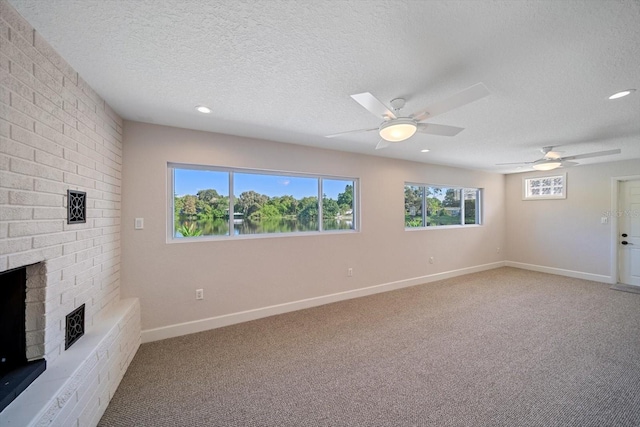 unfurnished living room featuring baseboards, light carpet, a fireplace, a textured ceiling, and a ceiling fan