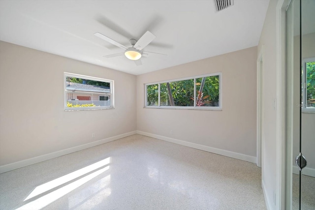 empty room with visible vents, ceiling fan, speckled floor, and baseboards