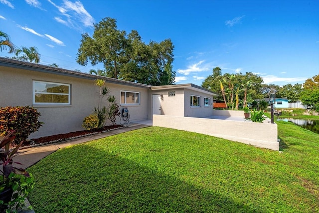 back of house featuring stucco siding, a patio, and a yard