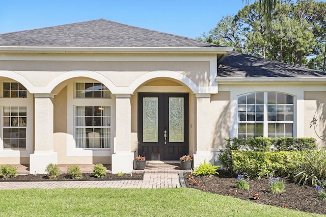 doorway to property with stucco siding, french doors, and roof with shingles