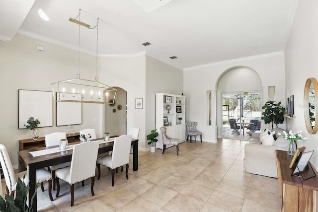 dining space with arched walkways, visible vents, crown molding, and a towering ceiling