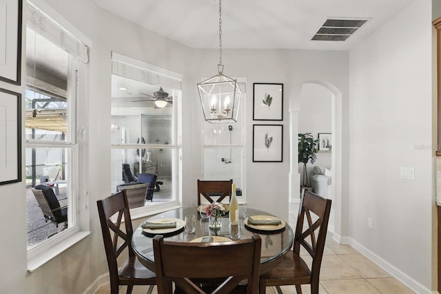 dining space featuring light tile patterned floors, a ceiling fan, visible vents, baseboards, and arched walkways