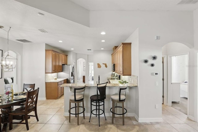 kitchen with visible vents, a kitchen bar, arched walkways, appliances with stainless steel finishes, and a peninsula