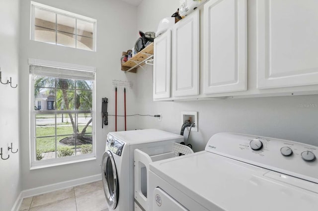 clothes washing area with light tile patterned floors, baseboards, cabinet space, and separate washer and dryer