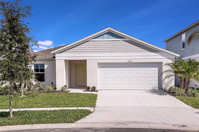 single story home featuring stucco siding, driveway, an attached garage, and a front yard