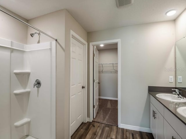 full bathroom featuring visible vents, wood finished floors, walk in shower, and a sink