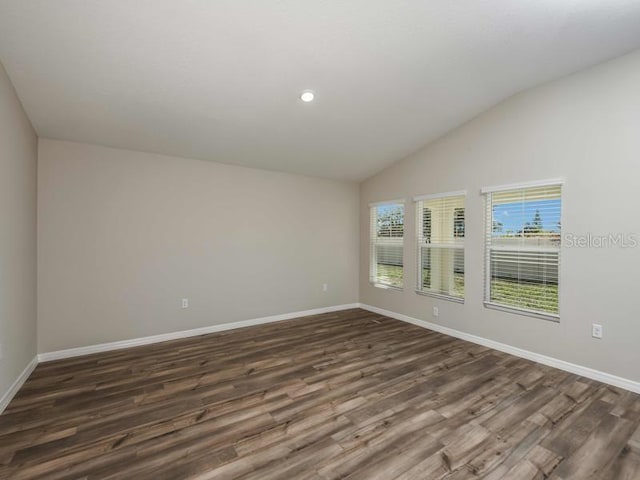 unfurnished room with dark wood finished floors, baseboards, and lofted ceiling