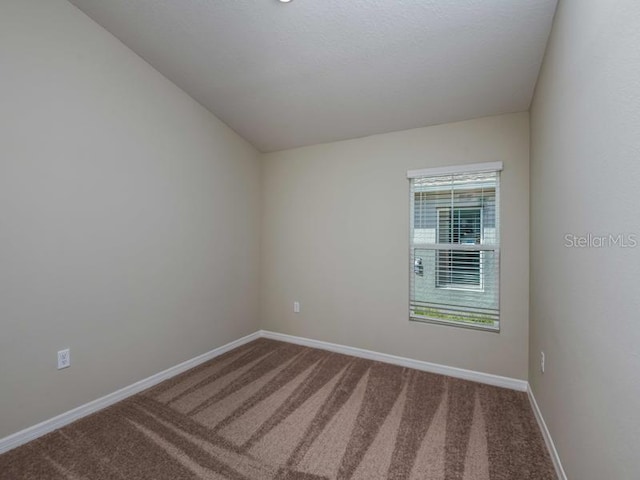 carpeted spare room with baseboards and vaulted ceiling