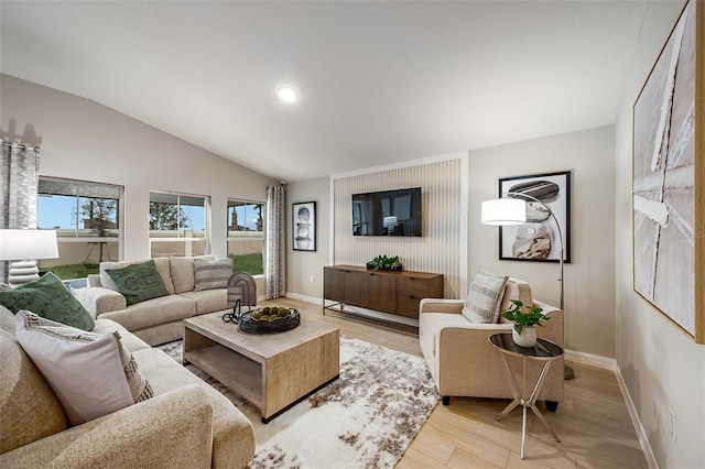 living room featuring vaulted ceiling, light wood-style floors, and baseboards