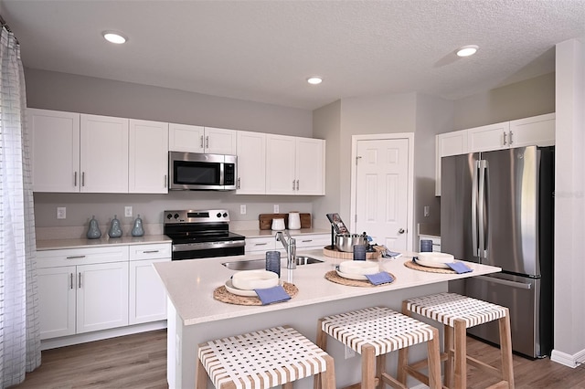 kitchen featuring white cabinetry, stainless steel appliances, light countertops, and a sink