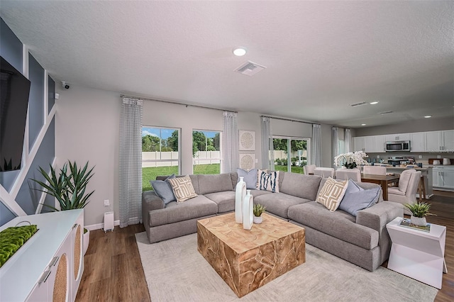 living area with dark wood-type flooring, recessed lighting, visible vents, and a textured ceiling