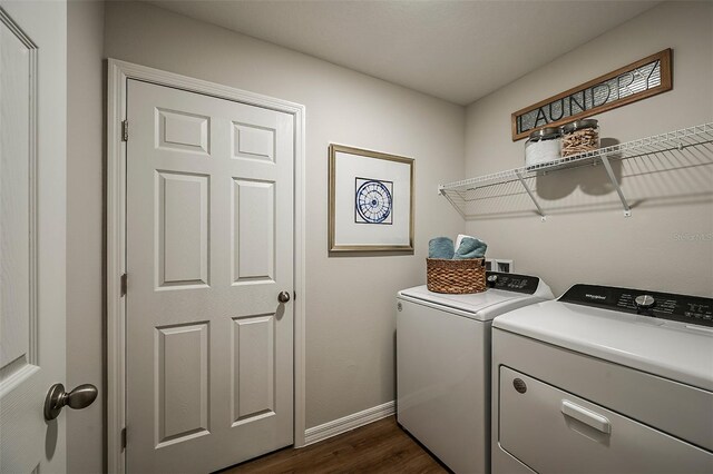 clothes washing area with laundry area, baseboards, dark wood-type flooring, and washing machine and clothes dryer