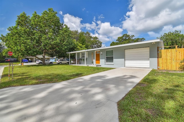 view of front of home with driveway, a front lawn, an attached garage, and fence