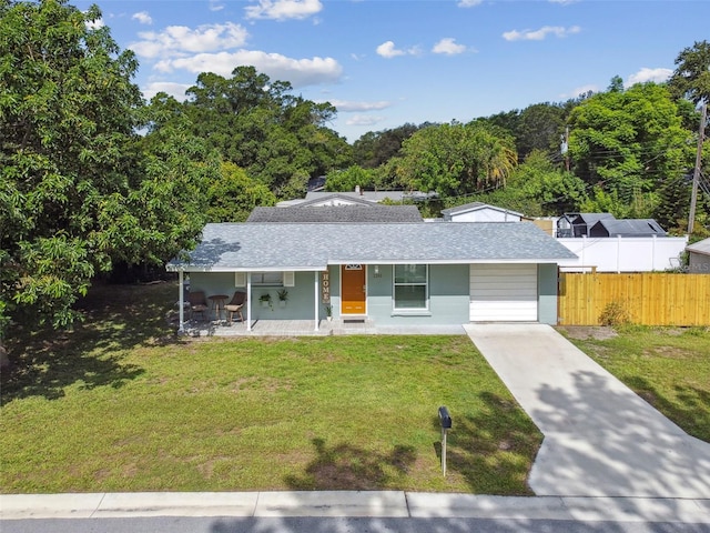 ranch-style home featuring a shingled roof, a front lawn, fence, concrete driveway, and covered porch