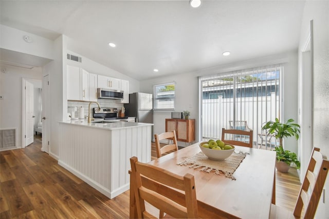 dining room featuring visible vents, lofted ceiling, and wood finished floors