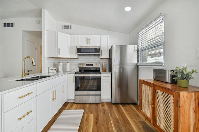 kitchen with vaulted ceiling, visible vents, appliances with stainless steel finishes, and a sink