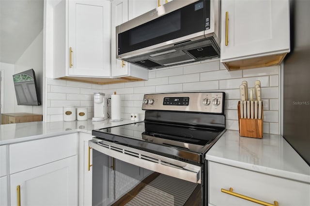 kitchen with decorative backsplash, white cabinets, light stone countertops, and stainless steel appliances