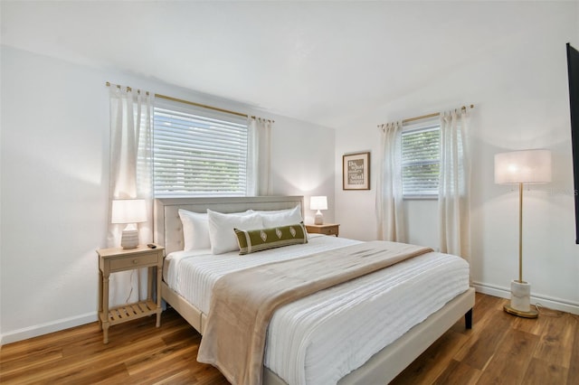 bedroom featuring baseboards, wood finished floors, and vaulted ceiling