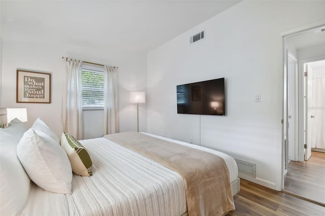 bedroom featuring visible vents, baseboards, and wood finished floors