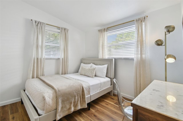 bedroom featuring baseboards, multiple windows, wood finished floors, and vaulted ceiling