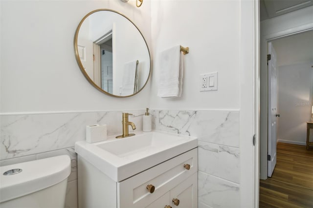 bathroom featuring a wainscoted wall, toilet, tile walls, and vanity