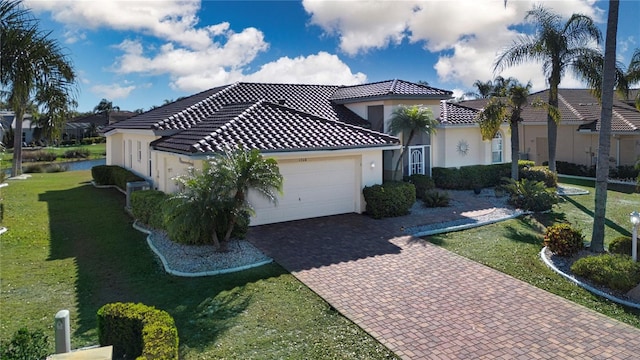 view of front of house featuring a front yard, an attached garage, stucco siding, a tiled roof, and decorative driveway