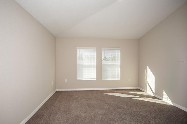 spare room featuring carpet flooring, baseboards, and vaulted ceiling