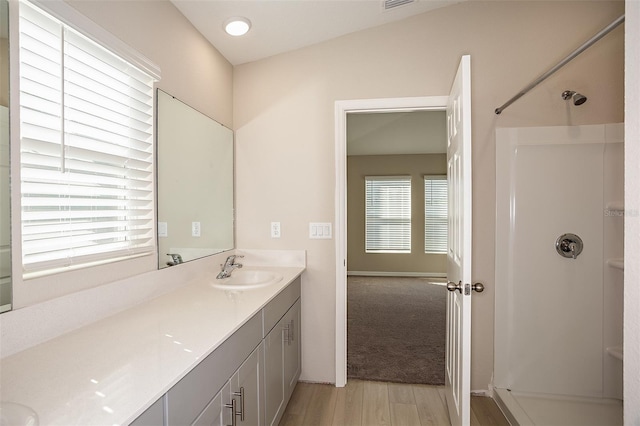 bathroom with visible vents, vanity, walk in shower, and wood finished floors